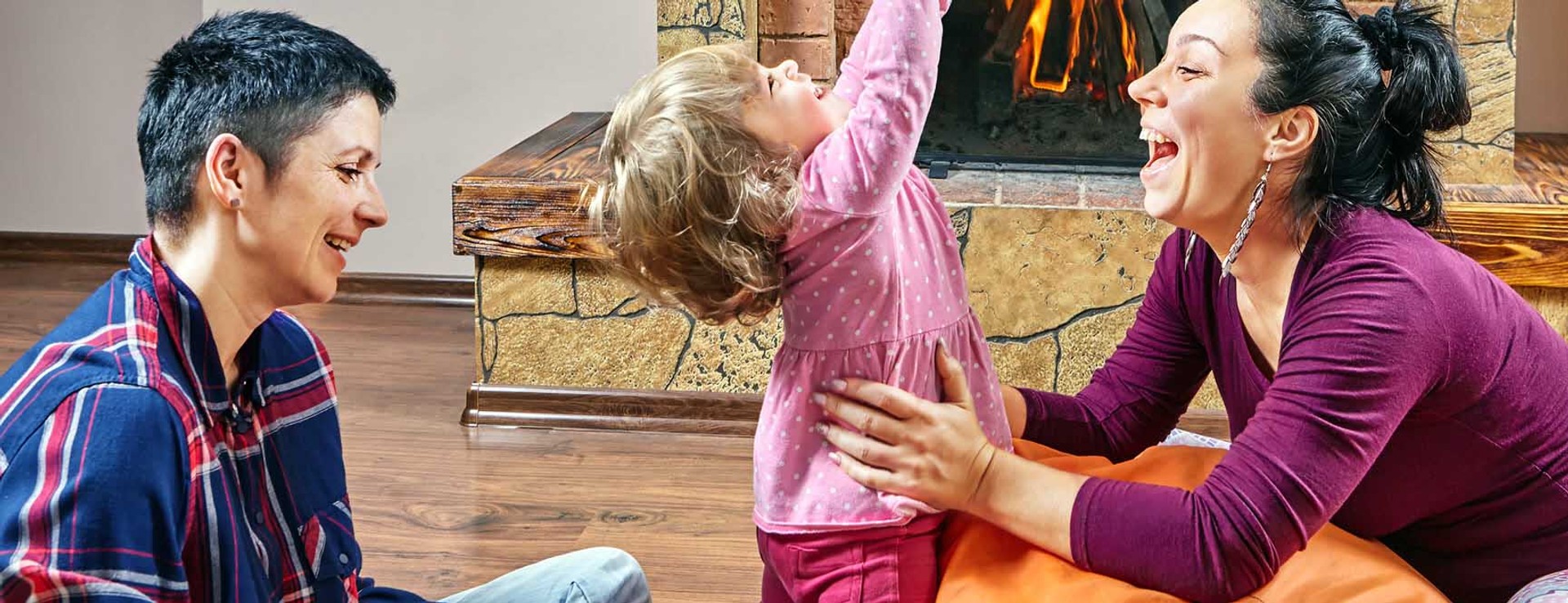 couple playing with child in front of fireplace
