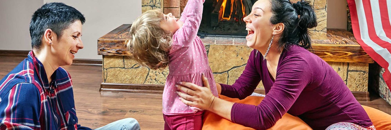 couple playing with child in front of fireplace