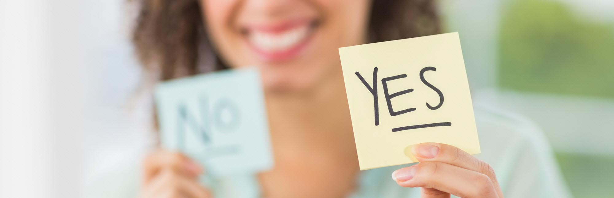 Woman holds two pieces of paper that say Yes and No